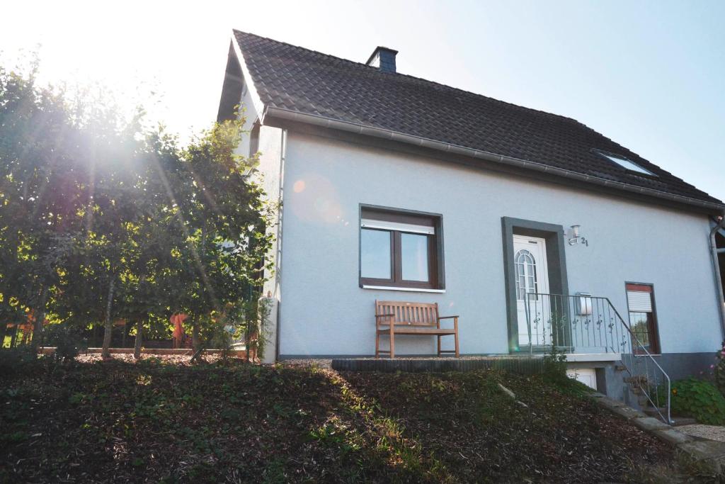 a white house with a bench in front of it at Ferienhaus am Nationalpark Eifel in Dreiborn