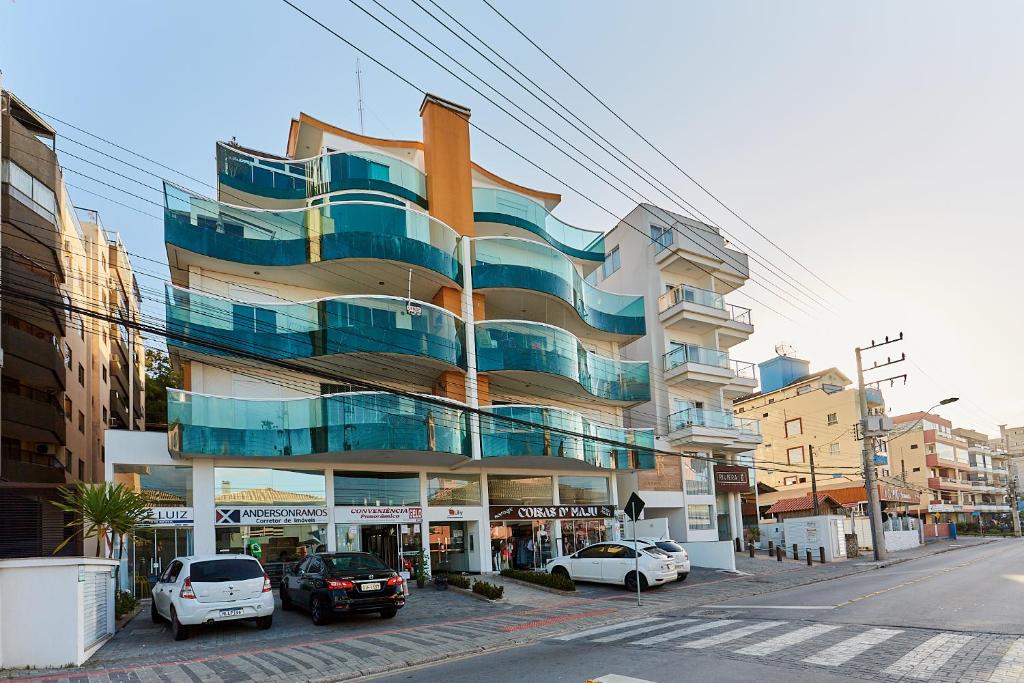 ein Gebäude mit davor geparkten Autos in der Unterkunft 1054 - Apartamento Centro de Bombinhas - Vista Mar - 1 Vaga Garagem - 50 metros Praia in Bombinhas