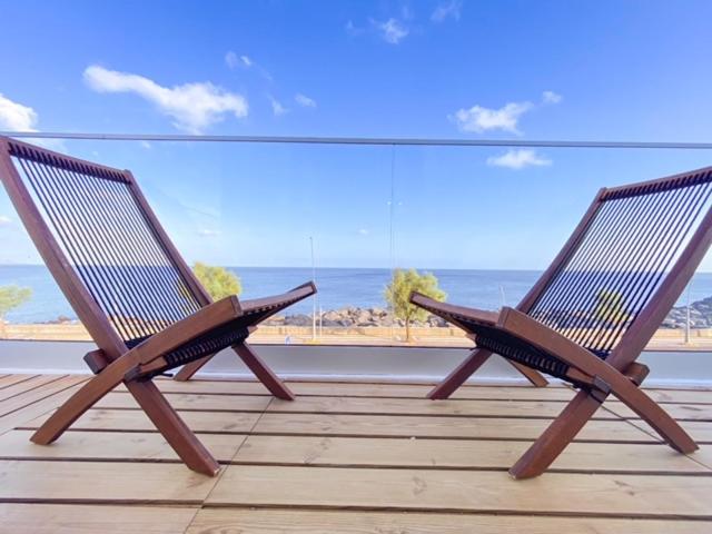 two chairs sitting on a balcony looking out at the beach at Pedra do Mar in São Roque