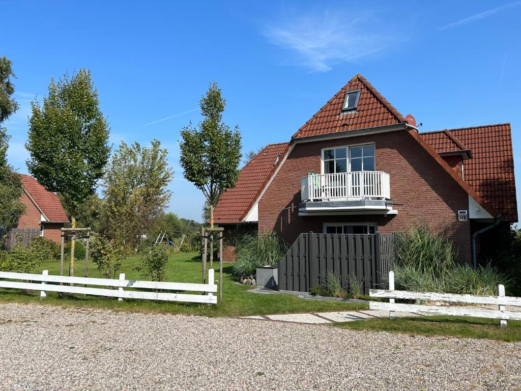 una casa con una cerca blanca delante de ella en Ferienwohnung Moby Dick, en Ording