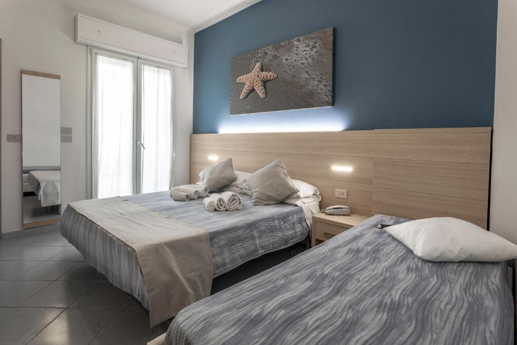 2 camas en una habitación con paredes azules en Hotel Esperia, en Cattolica