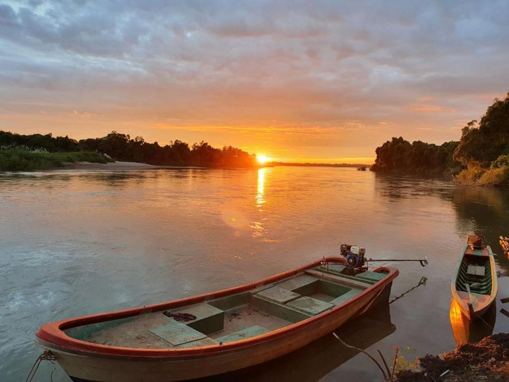 una barca seduta in acqua con il tramonto sullo sfondo di Angkor Bird Nest Resort 