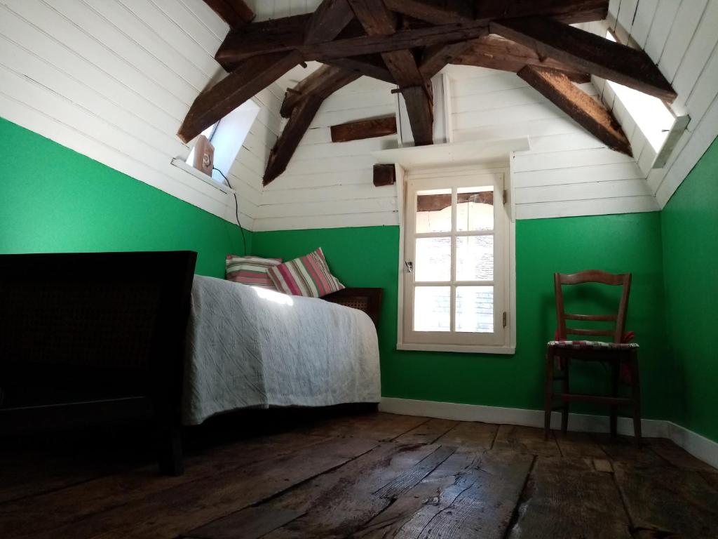 a bedroom with green walls and a bed and a window at Maison en plein cœur de ville à Montmorillon in Montmorillon