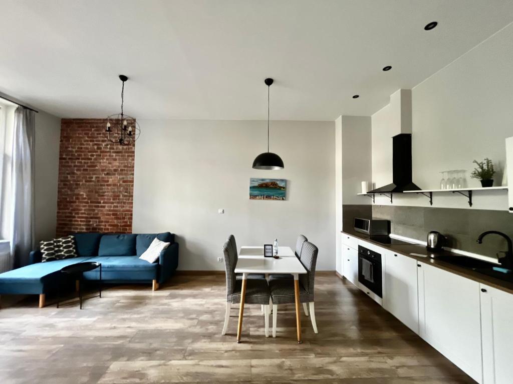 een keuken en een woonkamer met een tafel en een blauwe bank bij ACM Centrum Apartament z parkingiem in Bydgoszcz