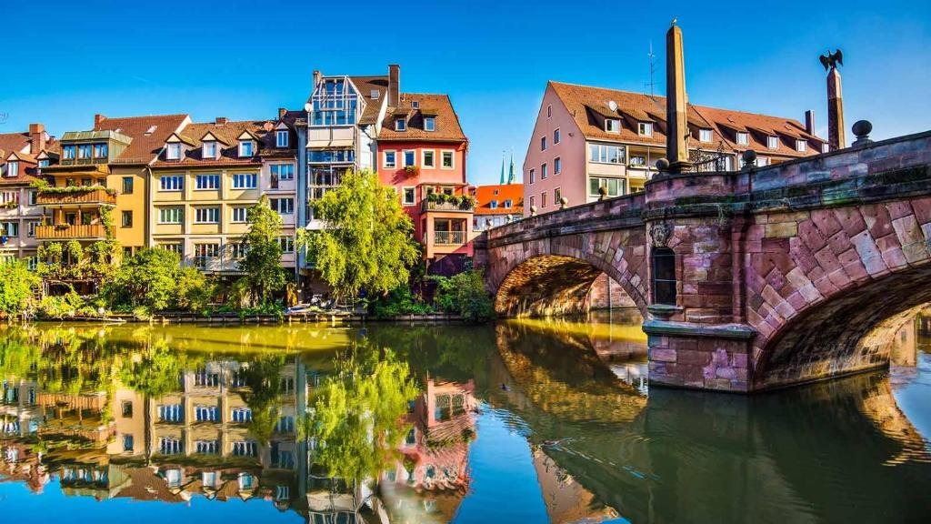 eine Brücke über einen Fluss in einer Stadt mit Gebäuden in der Unterkunft City Centre Apartment in Nürnberg