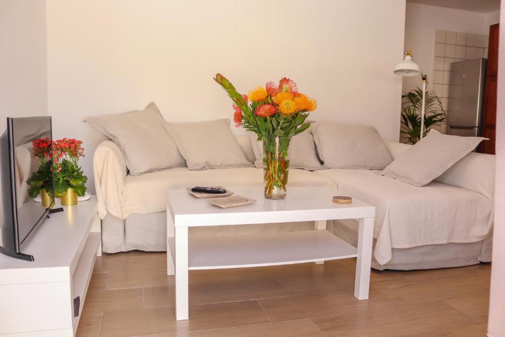 uma sala de estar com um sofá e um vaso de flores sobre uma mesa em Beatriz (C): Tranquilidad y playa. em Breña Baja