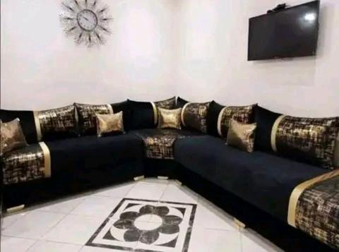 a black couch with pillows in a living room at شقة مفروشة in Temara