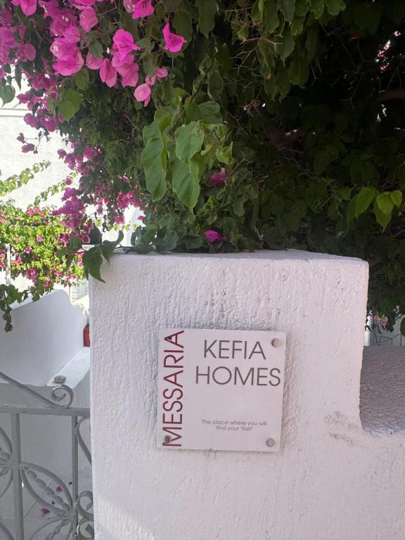 un cartel en una pared blanca con flores en Kefia 1 en Mesariá