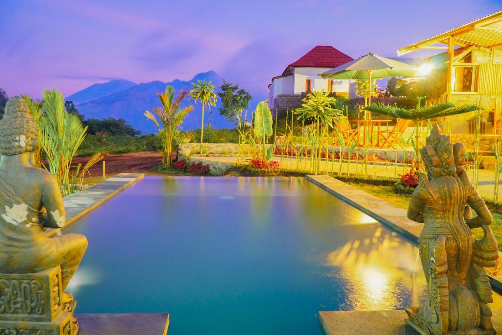 a swimming pool with two statues in front of a house at Pondok Bali Cottage in Kintamani