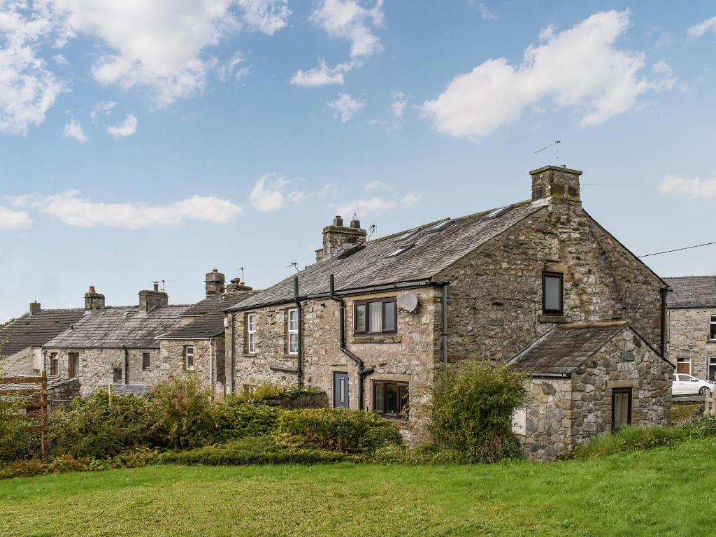 an old stone house on a grassy field at Gable End Cottage in Ingleton