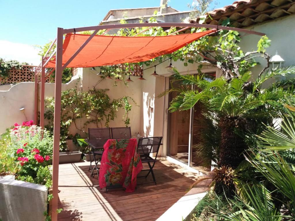 a patio with an orange umbrella and a table and chairs at Chez Marie in Carry-le-Rouet