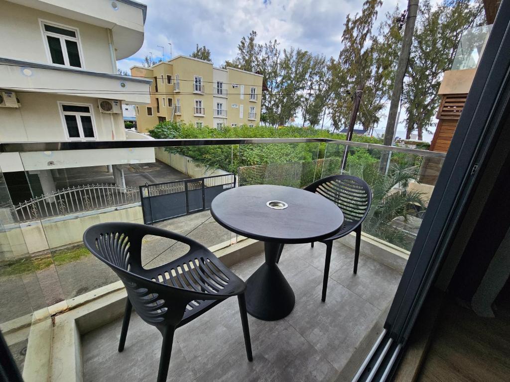 stół i 2 krzesła na balkonie ze stołem w obiekcie Beachfront Coziness w mieście Flic-en-Flac