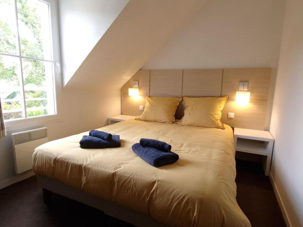 ein Schlafzimmer mit einem großen Bett mit zwei blauen Kissen darauf in der Unterkunft Nid d'Aven Charmante maison, piscine de février à octobre 1-6p dans résidence in Pont-Aven