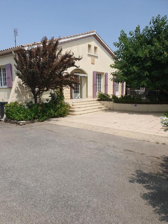 Una casa blanca con un árbol delante. en Villa Gesinacris avec piscine en Camaret-sur-Aigues