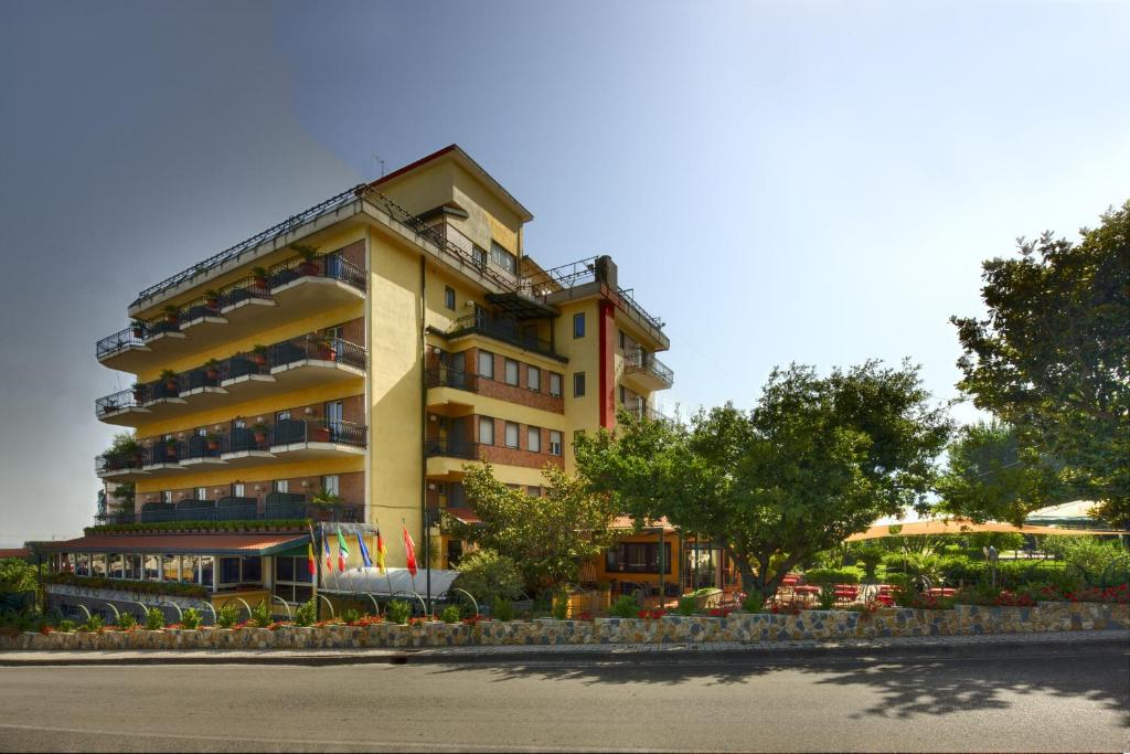 een groot geel gebouw met vlaggen ervoor bij Hotel Parco in Castellammare di Stabia
