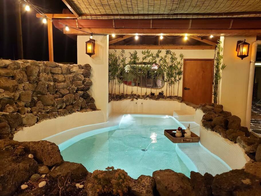 a large swimming pool in a room with a stone wall at Jeju Deluang Gimnyeong 1236 in Jeju