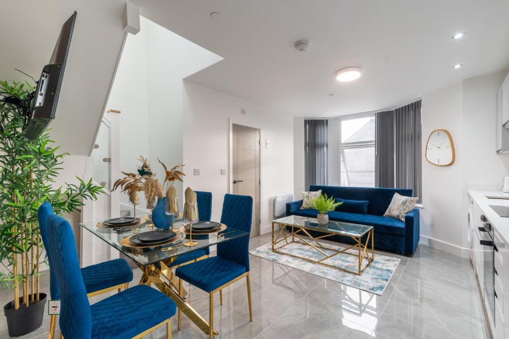 een woonkamer met een eettafel en blauwe stoelen bij Cardiff Luxe Living Apartments in Cardiff