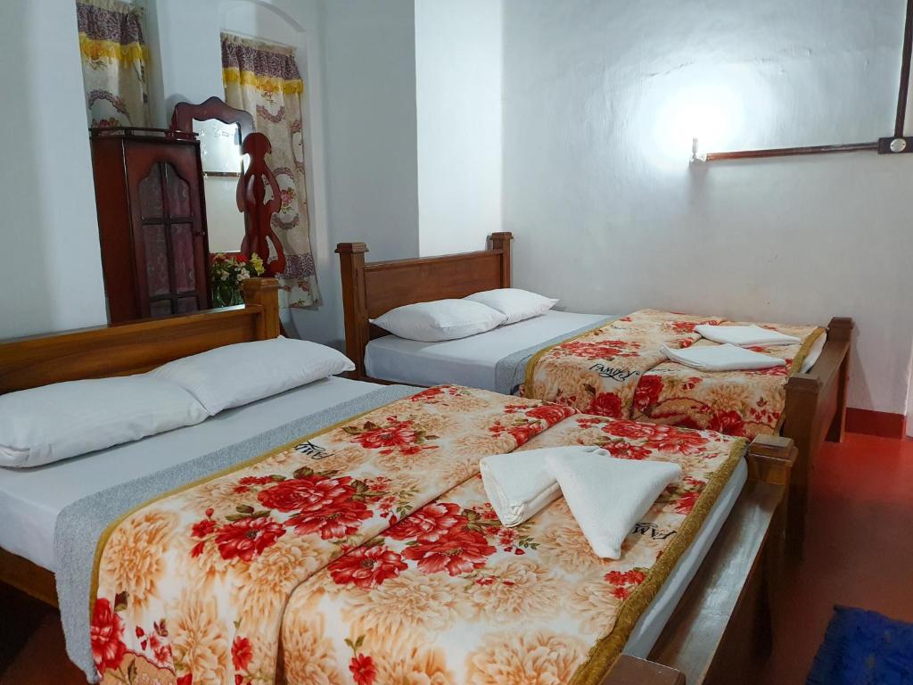 two beds in a hotel room with towels on them at Ruchi House in Nuwara Eliya