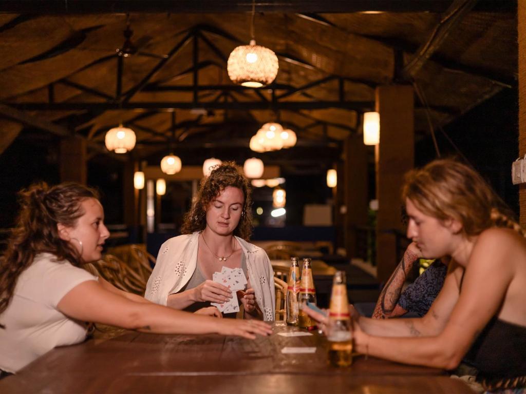 un grupo de mujeres sentadas en un bar con bebidas en Madpackers Goa en Anjuna