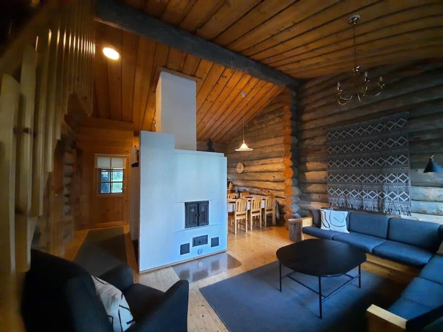 a living room with a blue couch and a fireplace at Lumi - kelohirsimökki Rukalla, log cabin at Ruka in Kuusamo