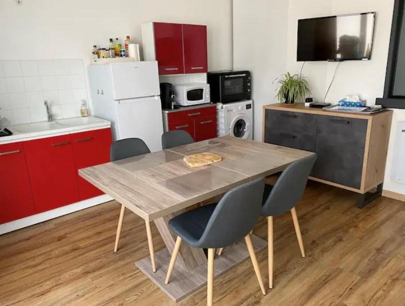 a kitchen with red cabinets and a wooden table and chairs at Joli T2 dans une maison de village in Chateauroux-les-Alpes