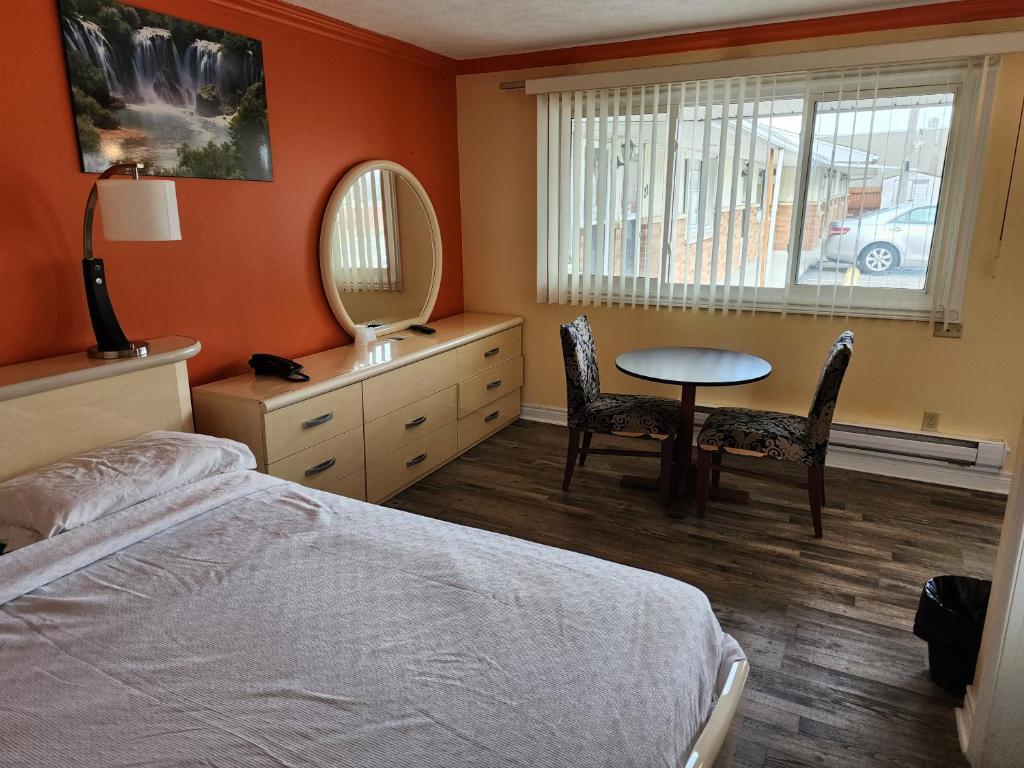 1 dormitorio con cama, mesa y espejo en Sunparlor Motel, en Leamington