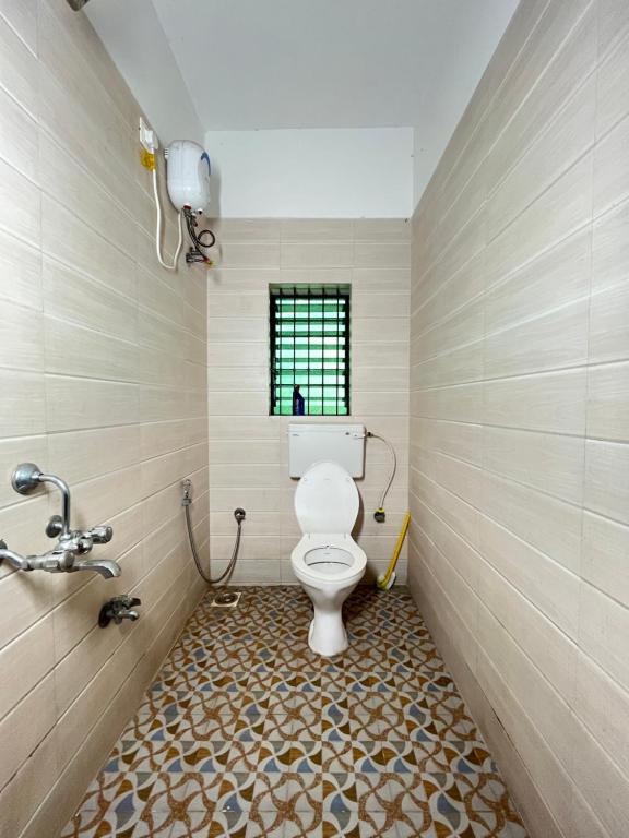 a bathroom with a toilet and a tiled floor at Mitra Homes - Mandrem in Mandrem
