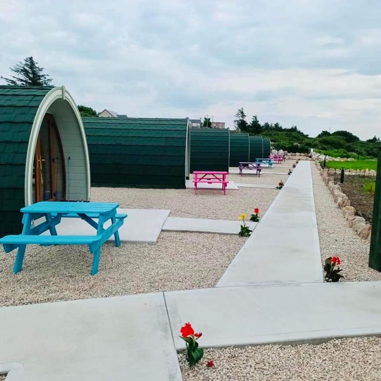 una fila di tavoli da picnic accanto a un edificio di Wheelhousepods glamping a Donegal