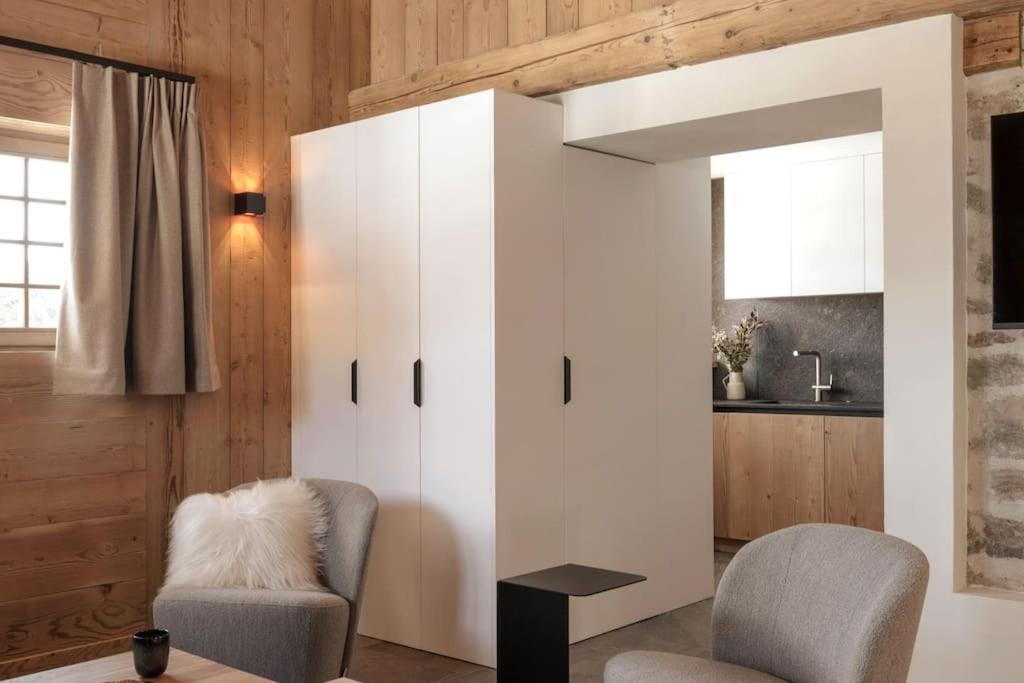 a living room with a white cabinet and two chairs at Appartement Rémy - at the foot of the slopes in Saint-Gervais-les-Bains