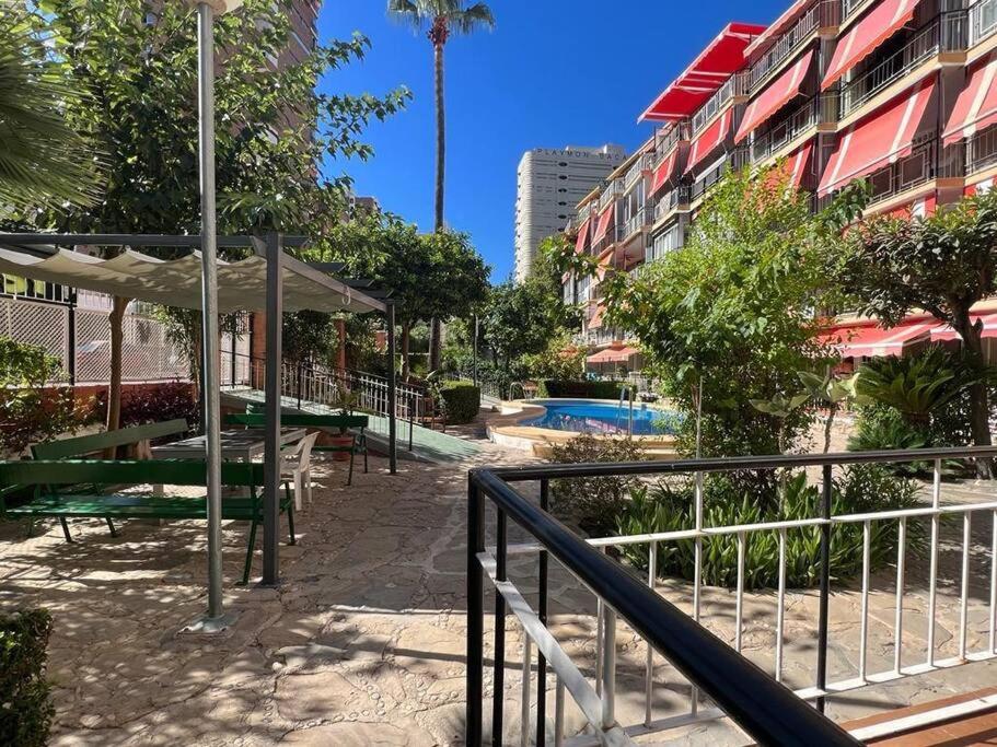 une allée avec des tables et des bancs à côté d'un bâtiment dans l'établissement 2 linea de playa con piscina, jardín, terraza y parking, à Benidorm