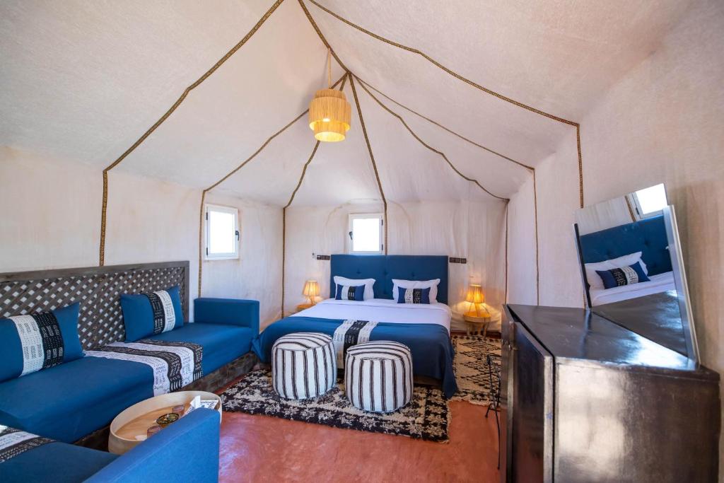 a bedroom with a bed and a couch in a tent at Golden Camp & Oasis in Merzouga