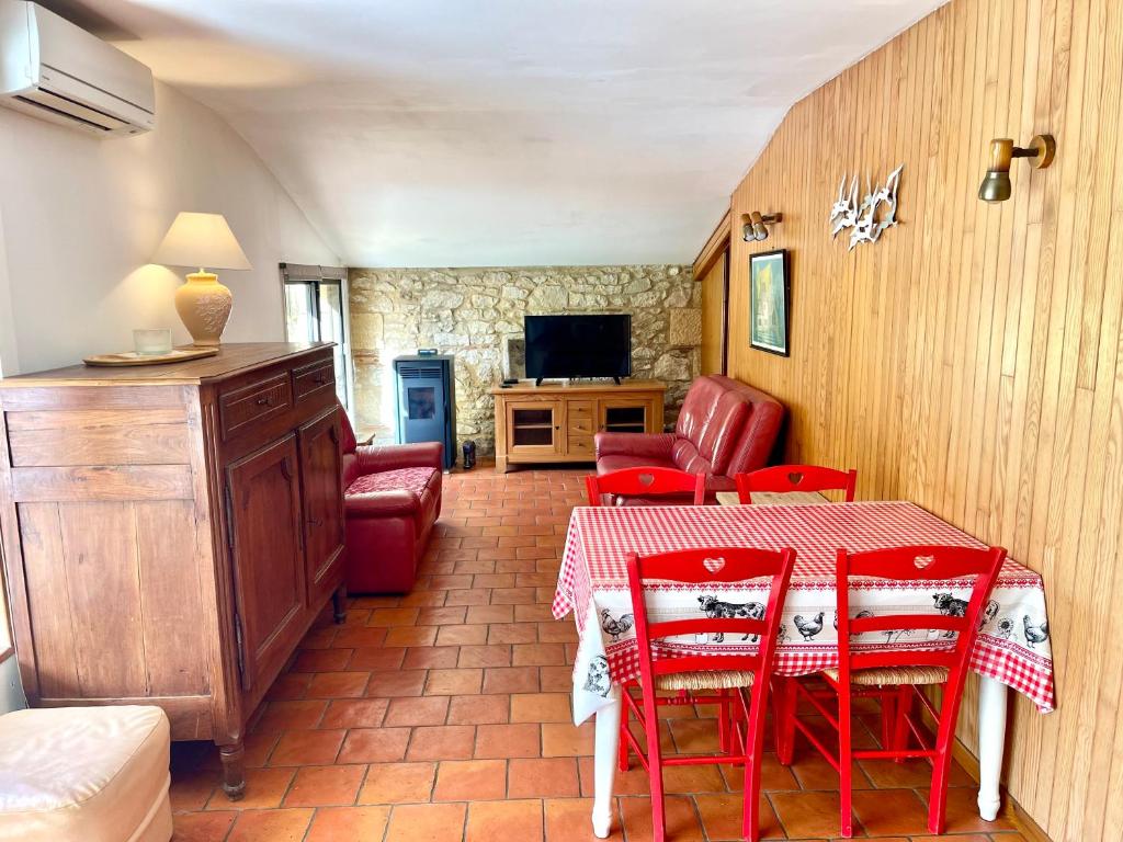 una sala da pranzo con tavolo e sedie rosse di Gite de charme en pierres apparentes : Les Granges a Gardonne