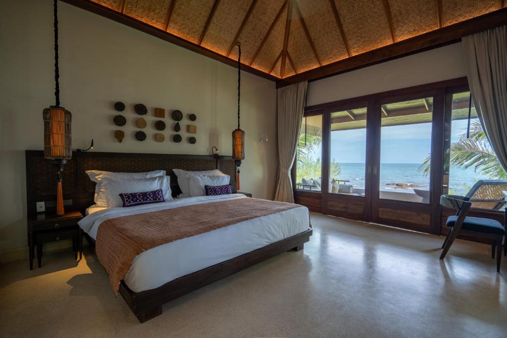 a bedroom with a bed with a view of the ocean at Samed Tamarind Beach Resort in Ko Samed