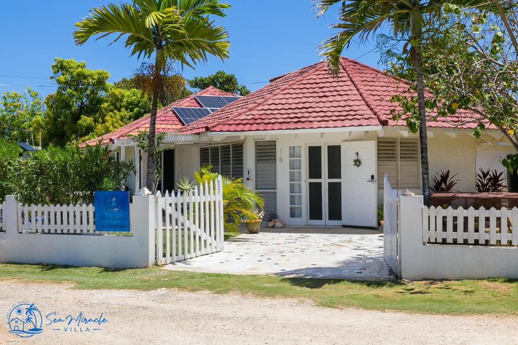 a house with a white fence and palm trees at Sea Miracle Villa/Beach Cottage in Silver Sands