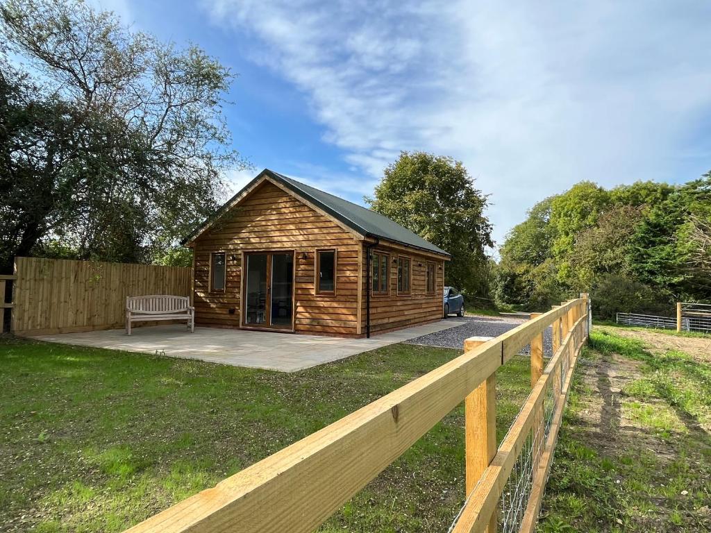 Cabaña de madera pequeña con valla de madera en Lakeside Lodge, en Eastleigh