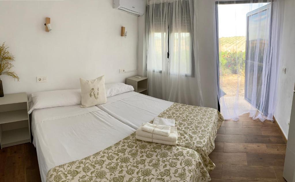 a bedroom with a large white bed and a window at FINCA VALDELAJARA a 20 minutos de Puy du Fou in Toledo