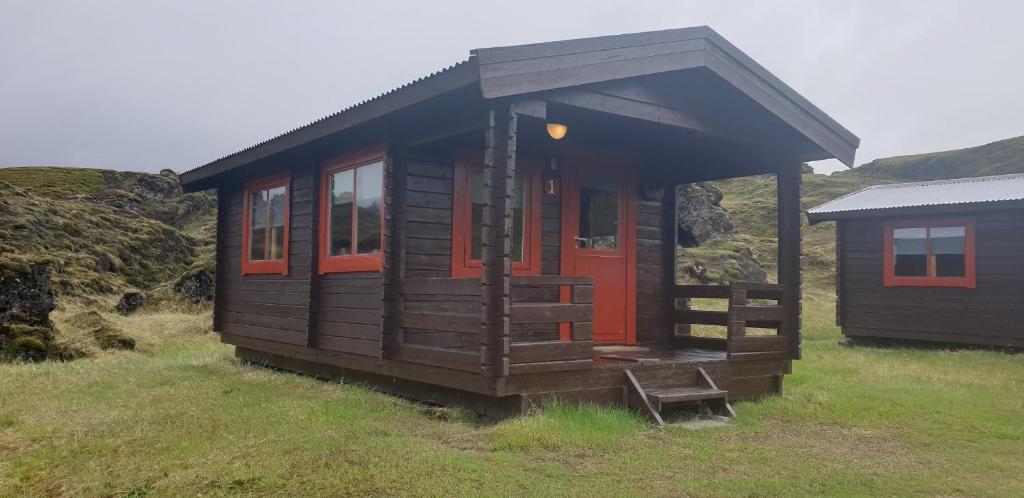 a small cabin with a red door in a field at Hólaskjól Highland Center in Kirkjubæjarklaustur