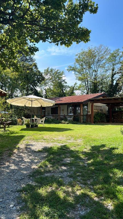 a house with a table and an umbrella in the grass at casetta in Varallo Pombia