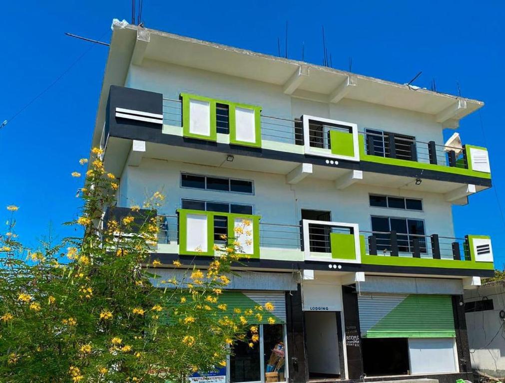 ein weißes Gebäude mit grünen Fenstern und einem Baum in der Unterkunft Ashirwad Homestay in Dibrugarh