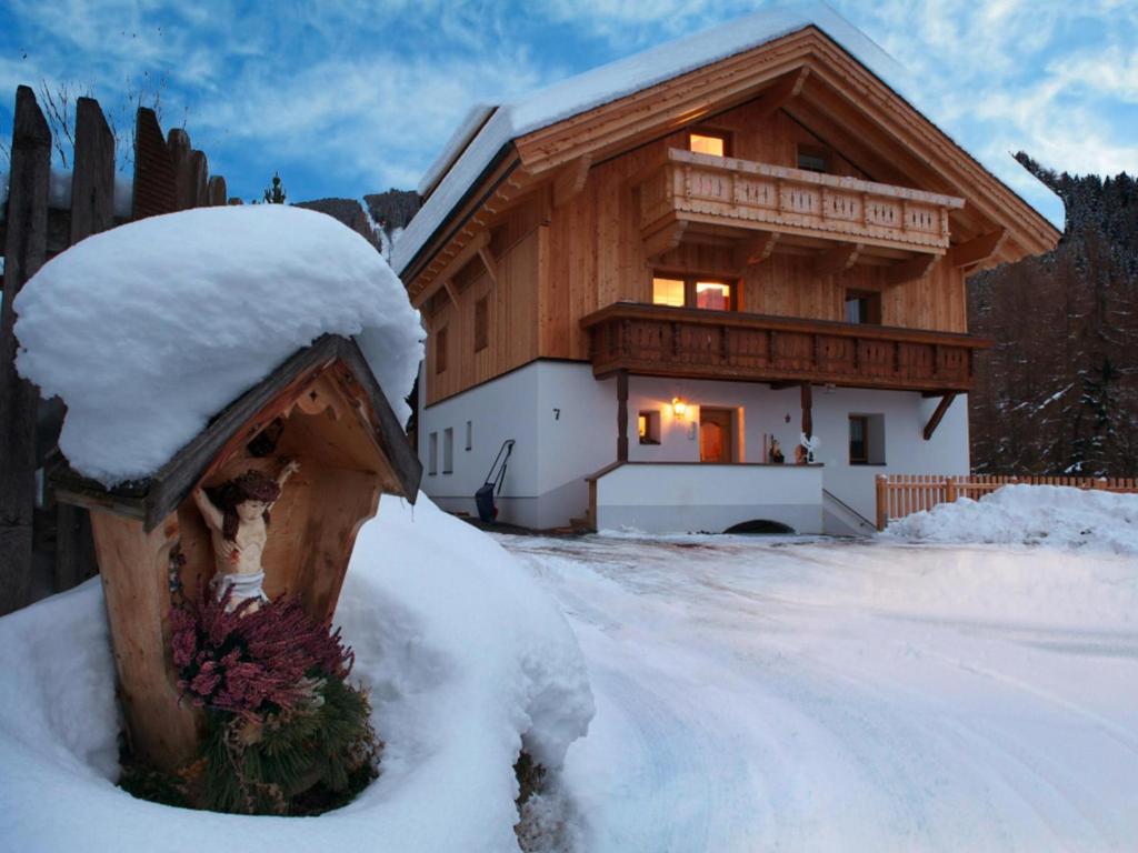 una cabaña de madera con nieve en la parte delantera en Kometer App Enzian, en Fendels