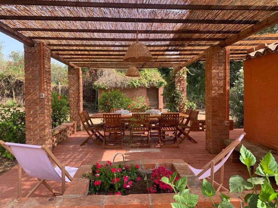 un patio con mesa y sillas bajo una pérgola de madera en l'ibiscus, en Brucoli