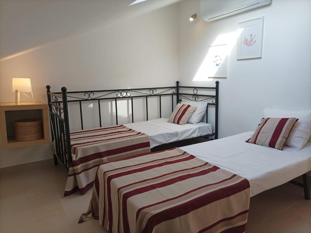 Duas camas num quarto com paredes brancas em Vila Gaio na Manta Rota