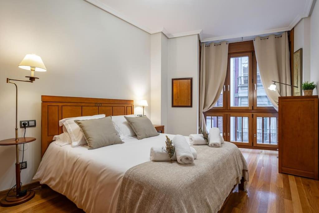 Un dormitorio con una gran cama blanca con almohadas blancas. en El Balcón de Santa Lucía, en Gijón