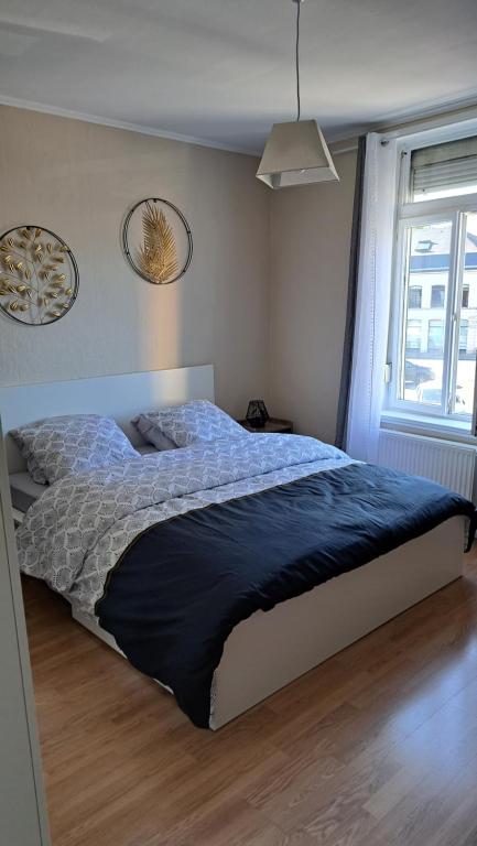 a bedroom with a bed with a blue comforter and a window at Chambre tout confort in Annappes