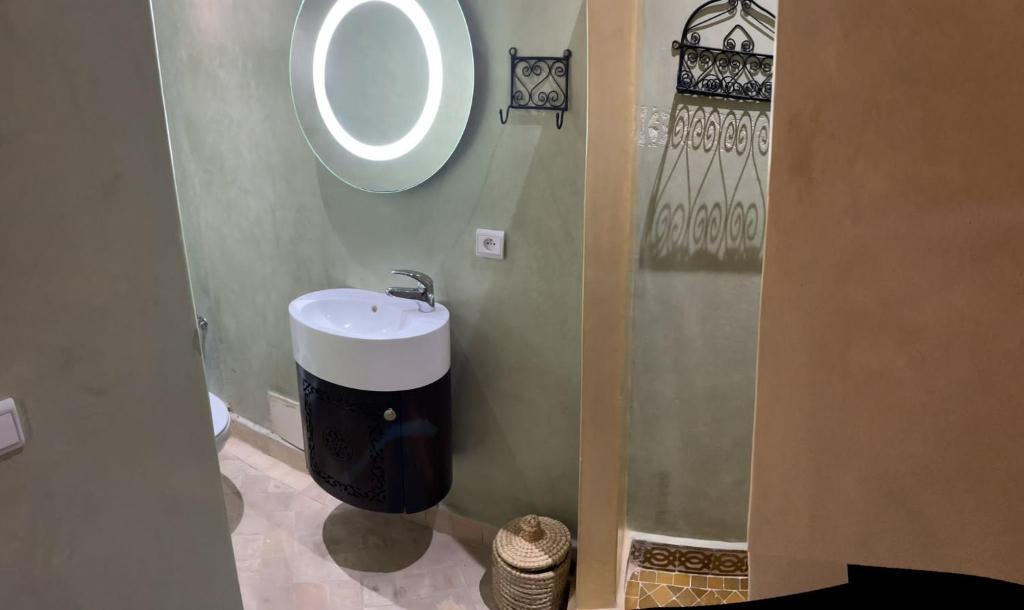 y baño con lavabo y espejo redondo. en RIAD LAICHI en Marrakech