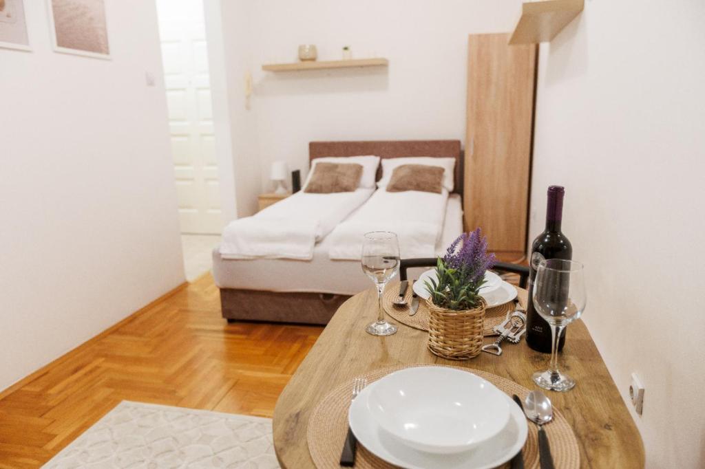 Cette chambre comprend un lit et une table avec des verres à vin. dans l'établissement Apartman 369, à Subotica