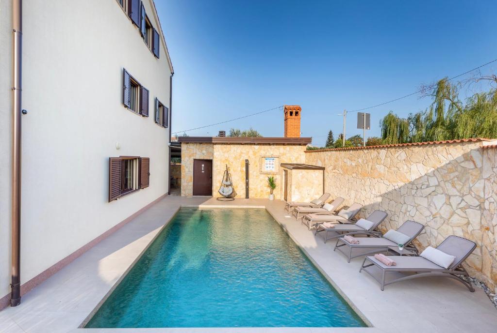uma piscina com espreguiçadeiras e uma casa em Villa Miromar em Pula