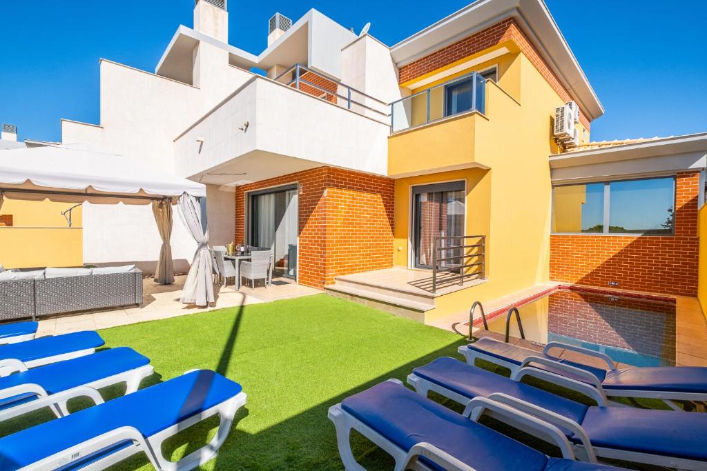 Un césped con sillas azules frente a una casa. en Cozy villa with pool and Barbecue, en Albufeira