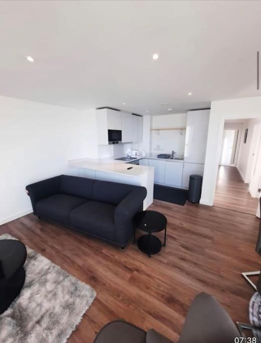 a living room with a couch and a kitchen at Luxurious 3 Bedroom Flat Close To East Croydon Station - Gym - Sleeps 6 in London