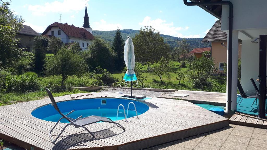 uma piscina com cadeiras e um guarda-sol num deque de madeira em Lepa Dolenjska em Uršna Sela